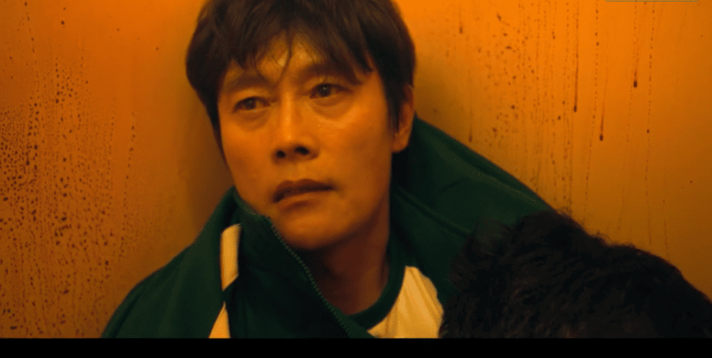 Squid Game 2: A person in a green jacket is looking at the camera