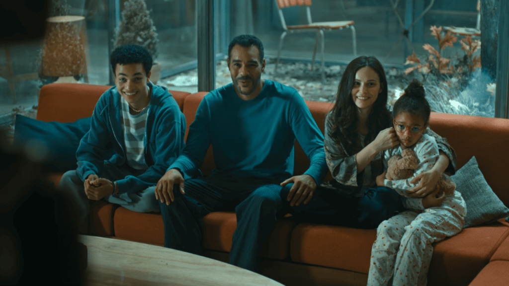 Cassandra Netflix Review: a family sitting on an orange couch in front of a window