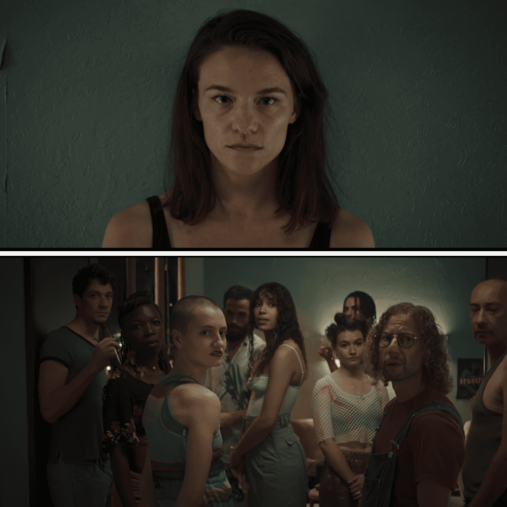 Delicious 2025 Review: A person is staring into the camera in a room full of people