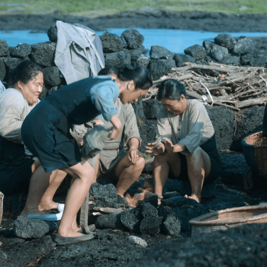When Life Gives You Tangerines Review: a group of people sitting around a fire