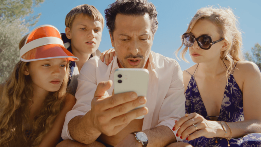 Delicious 2025 Review: A group looking at a cell phone.