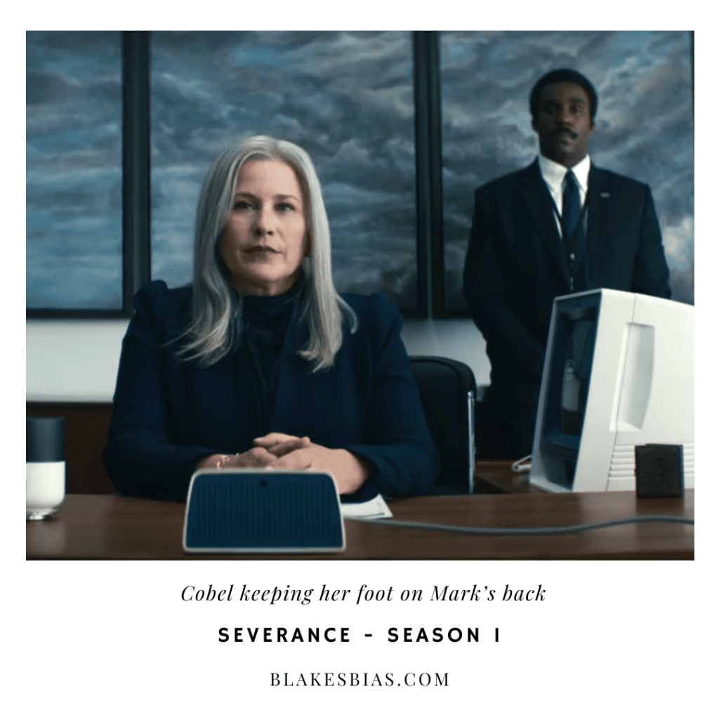 Best Severance Characters: A person sitting at a desk with two individuals behind them.