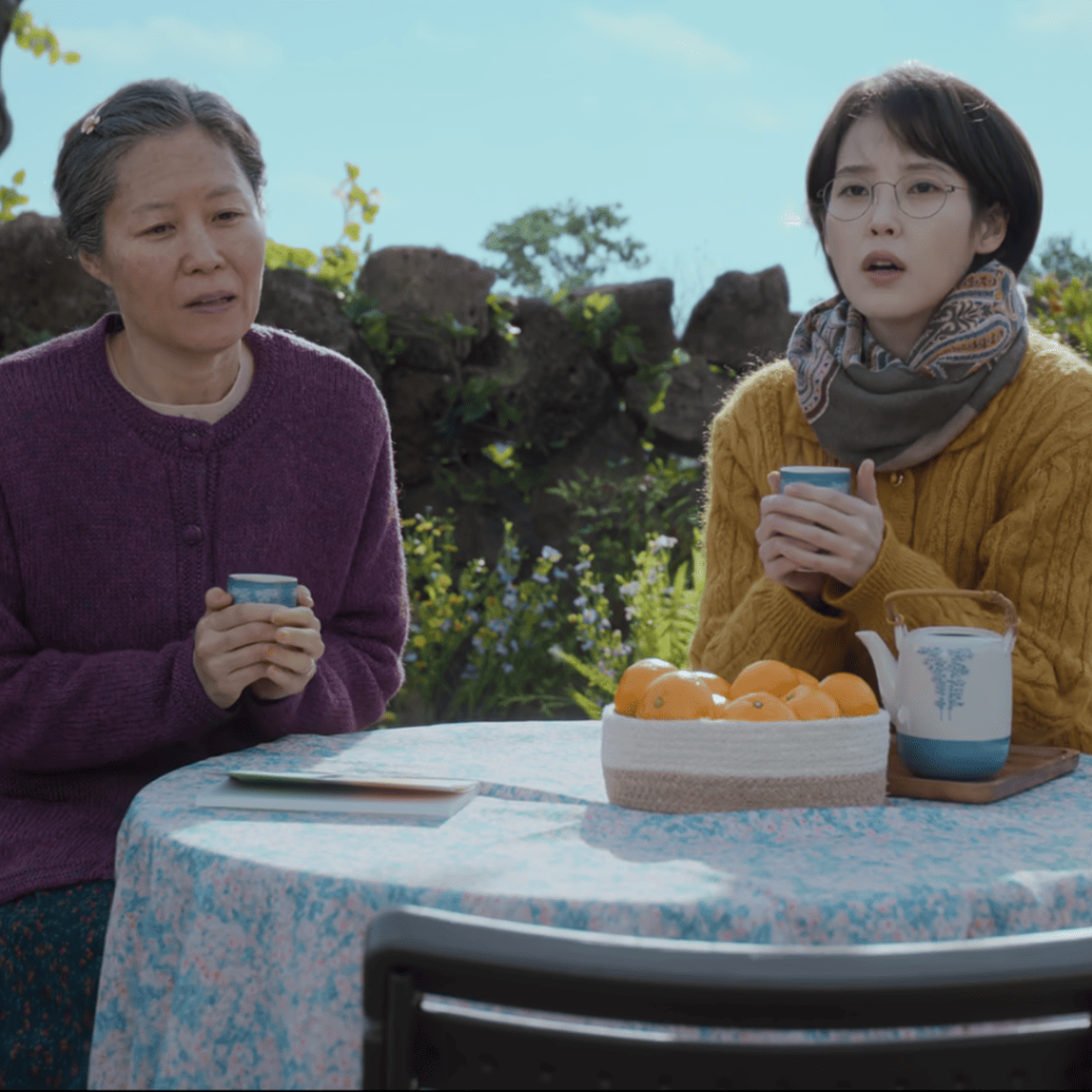 When Life Gives You Tangerines Full Review: two people sitting at a table holding cups