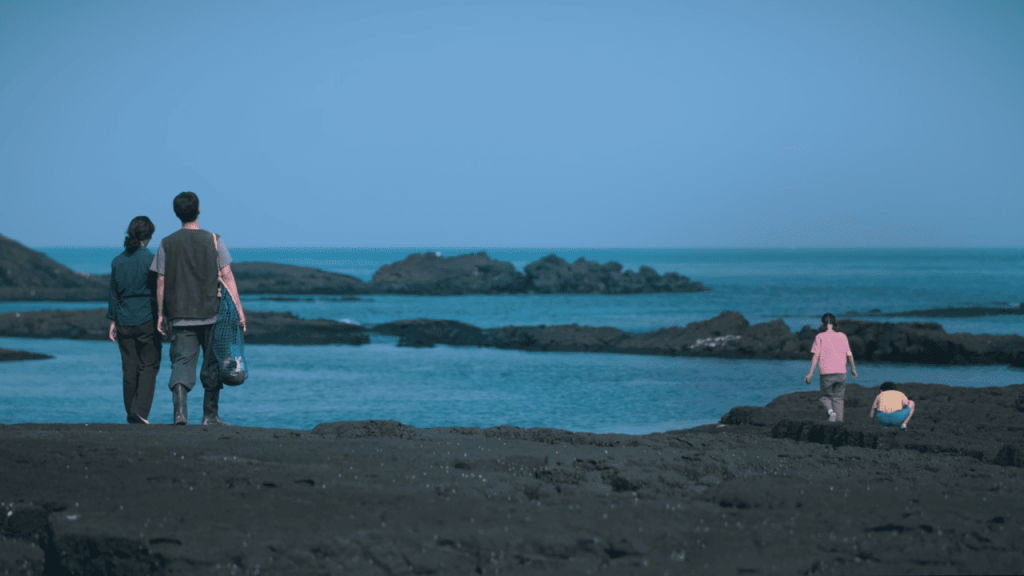 When Life Gives You Tangerines Full Review: three people standing on a rocky beach looking at the ocean