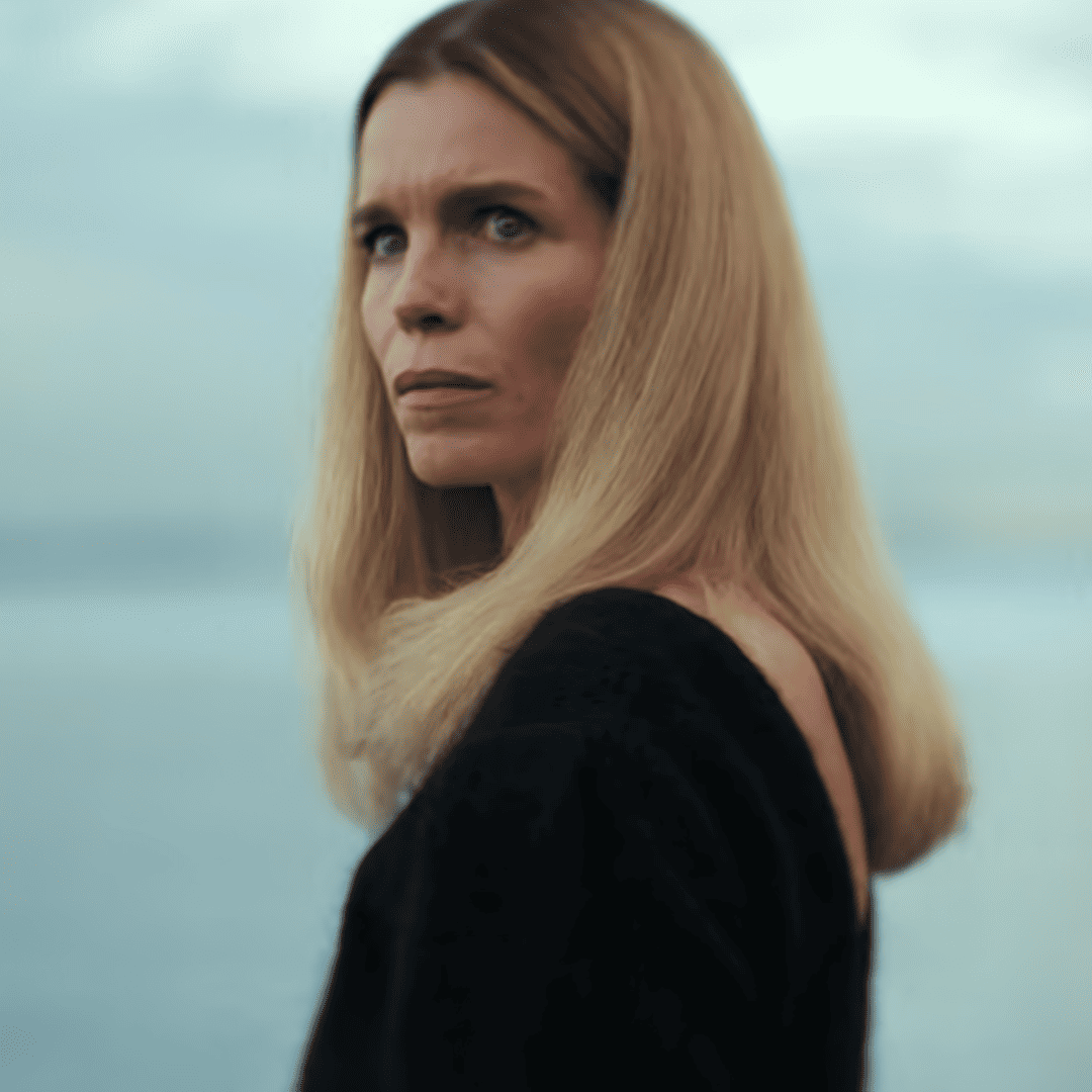 Secrets We Keep: A person with long blonde hair standing in front of the ocean