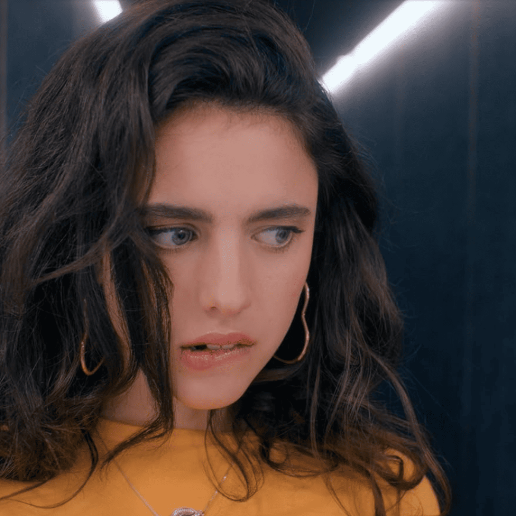 The Substance movie explained in a tense moment: Sue bites her lower lip, eyes heavy with conflict, caught in the agonizing choice to avoid swapping bodies with Elizabeth.