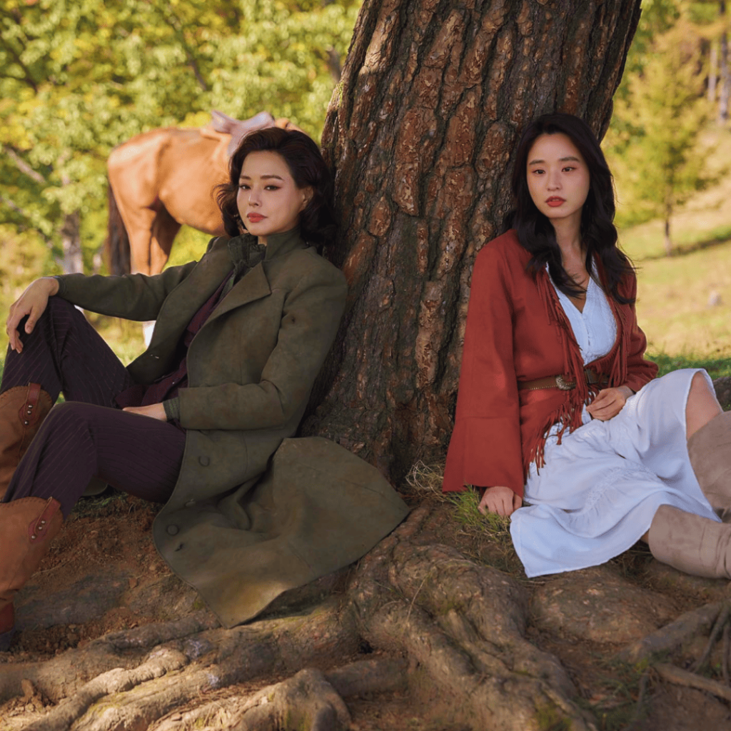 Aema Netflix Review – Hee Ra and Ju Ae in the final reflective scene by a tree.