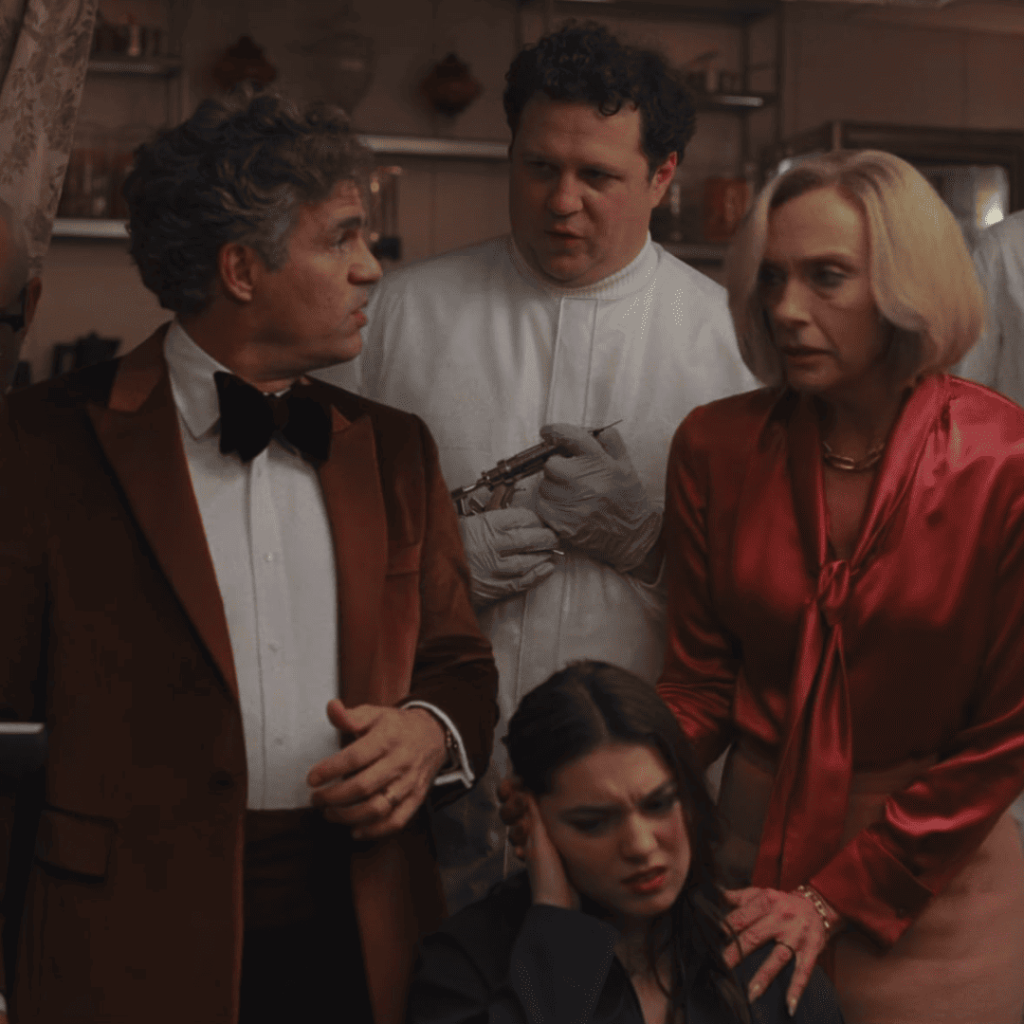 Mark Ruffalo, his wife, and Kai Katz at a tense dinner in Mickey 17, moments before poisoning Mickey.