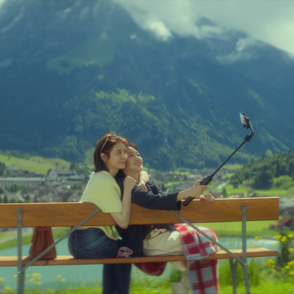 You and Everything Else Kdrama Review: Eun-jung and Sang-yeon sitting on a bench in the Swiss Alps, taking a selfie before Sang-yeon’s assisted suicide.