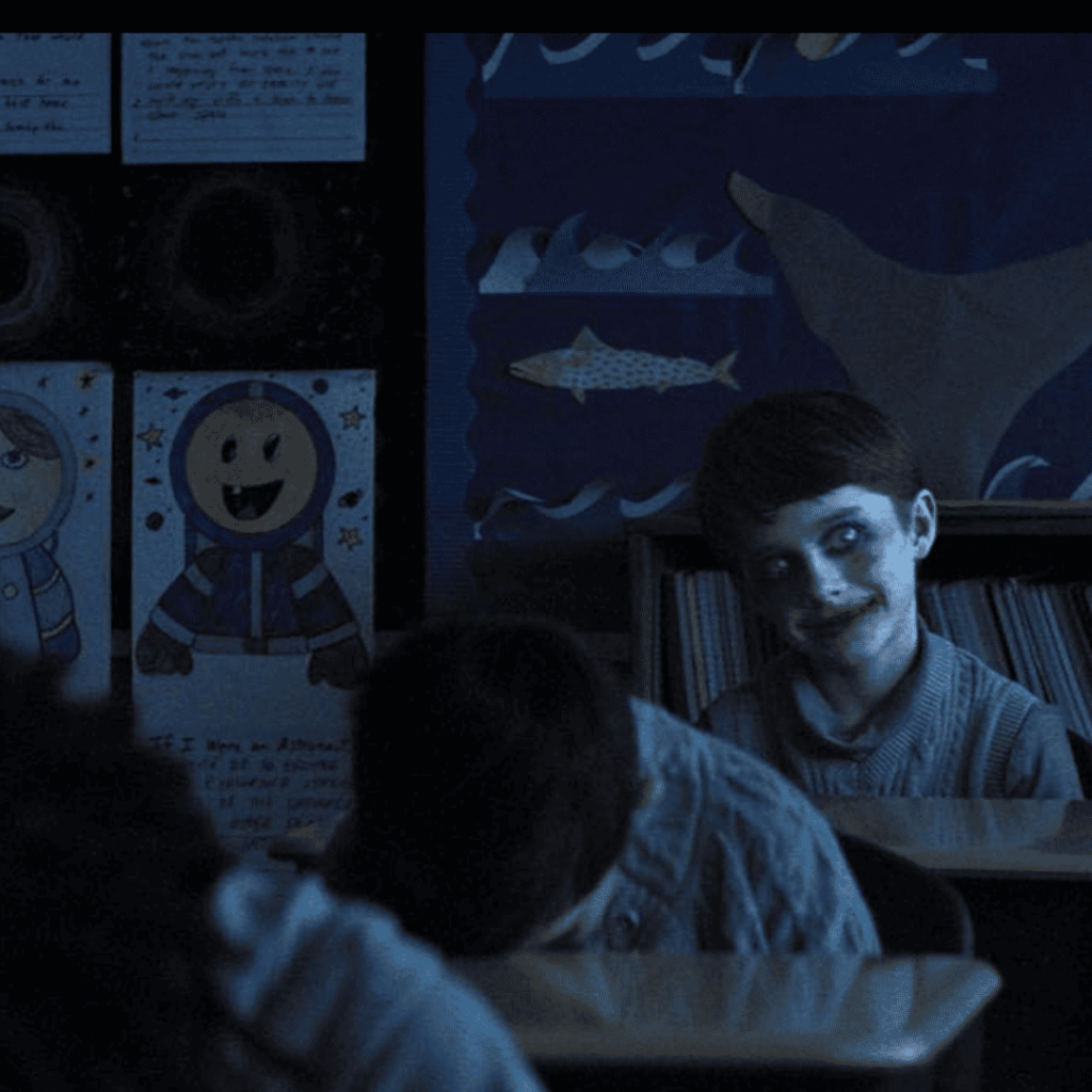 Weapons Movie Review still of Alex with creepy facepaint in the classroom while other kids rest their heads on desks