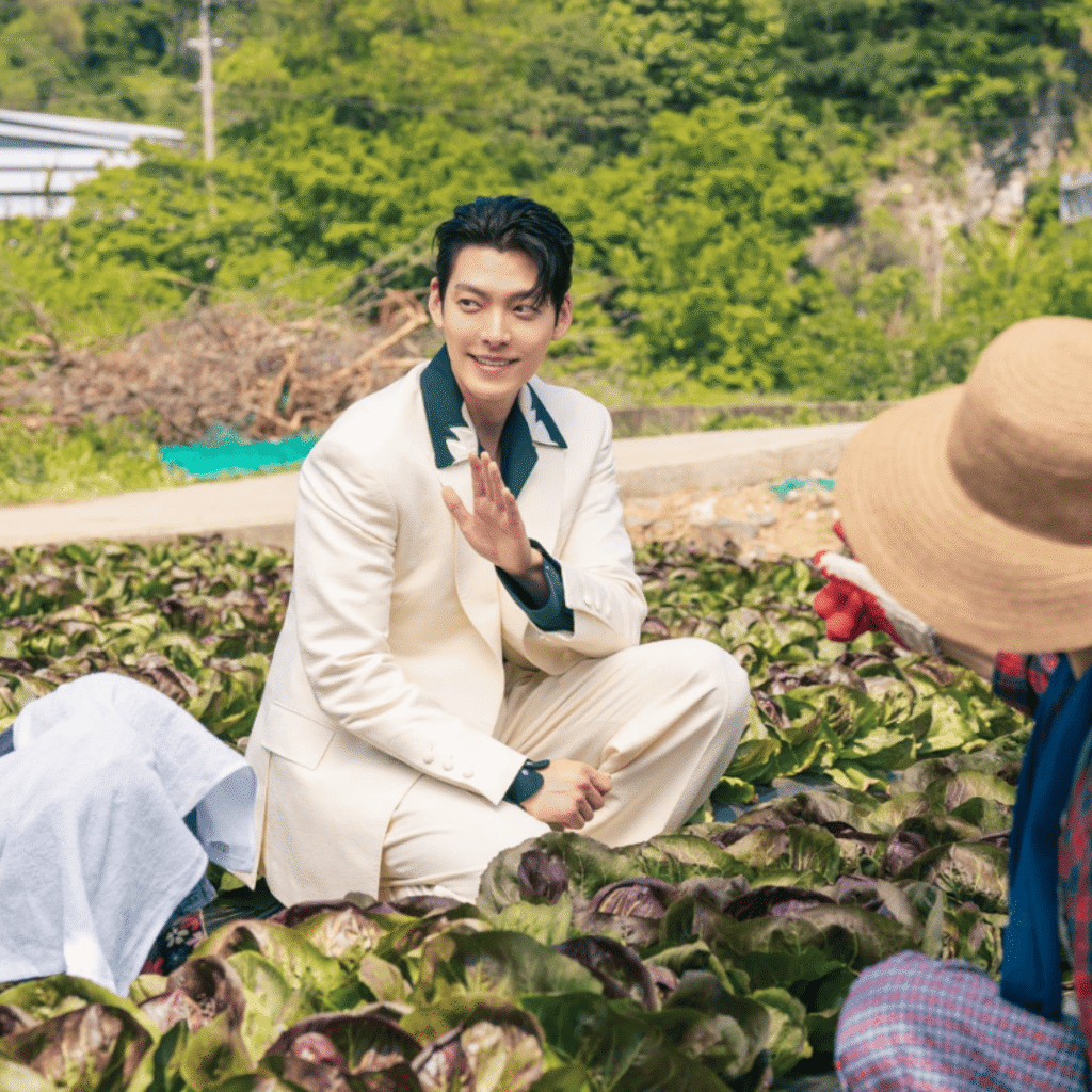 Genie Make-A-Wish Kdrama Review image of Iblis in a white suit sitting among the crops in the grandmother’s field after arriving in Korea.