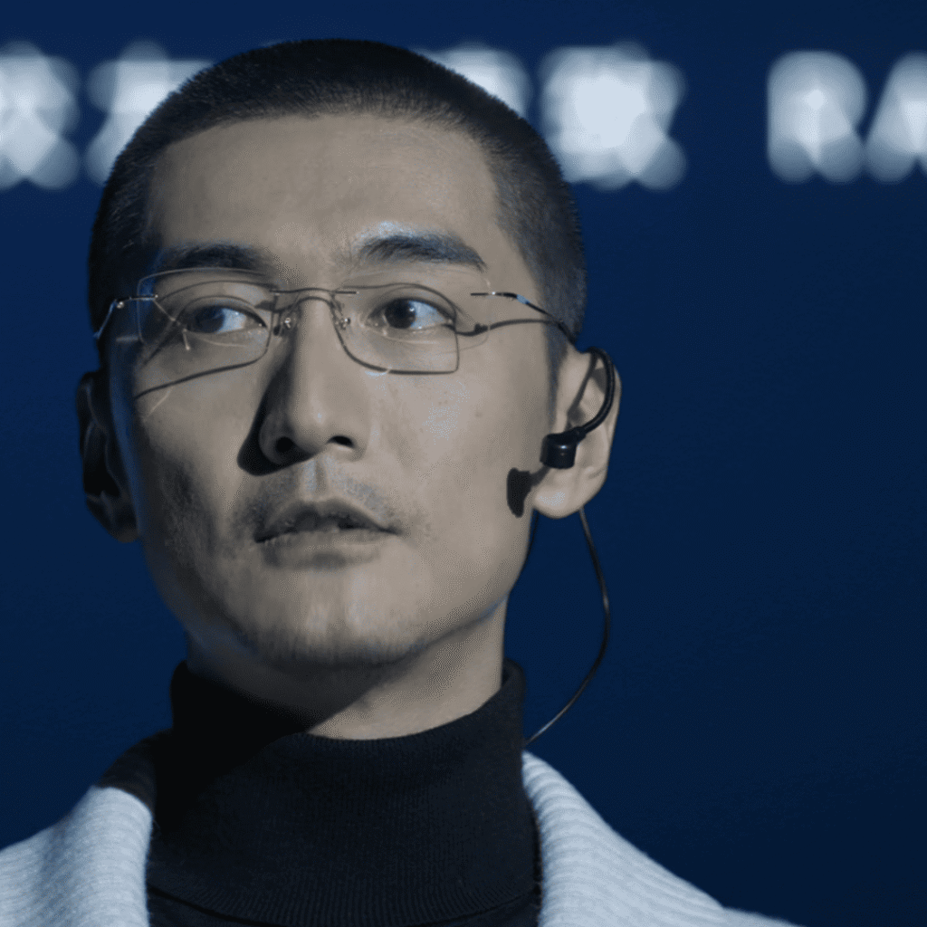 Mobius Mid-Season Review still of Mo Yuan Zhi speaking on a university stage under a blue backdrop, hinting at secrets beneath his calm