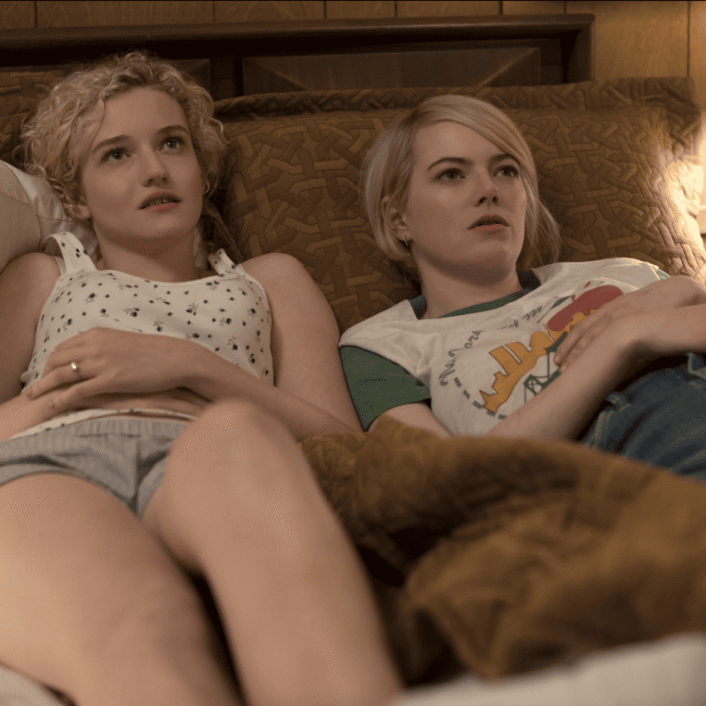 Maniac Review: Annie Landsberg and her sister, Ellie, lying side by side on a motel bed, staring up at the ceiling in a quiet, intimate moment of sisterly connection.