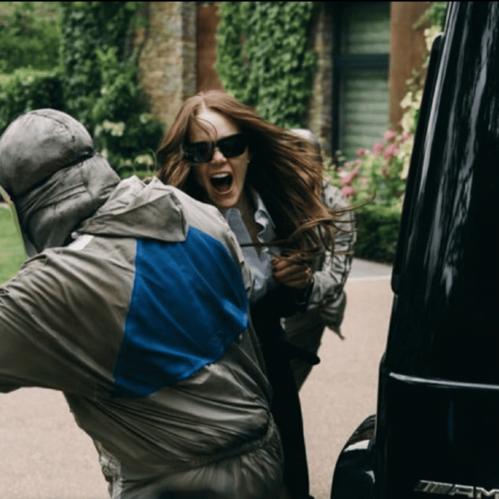 Bugonia Review: Michelle fighting off Teddy and Don beside her 4x4 during the kidnapping attempt.