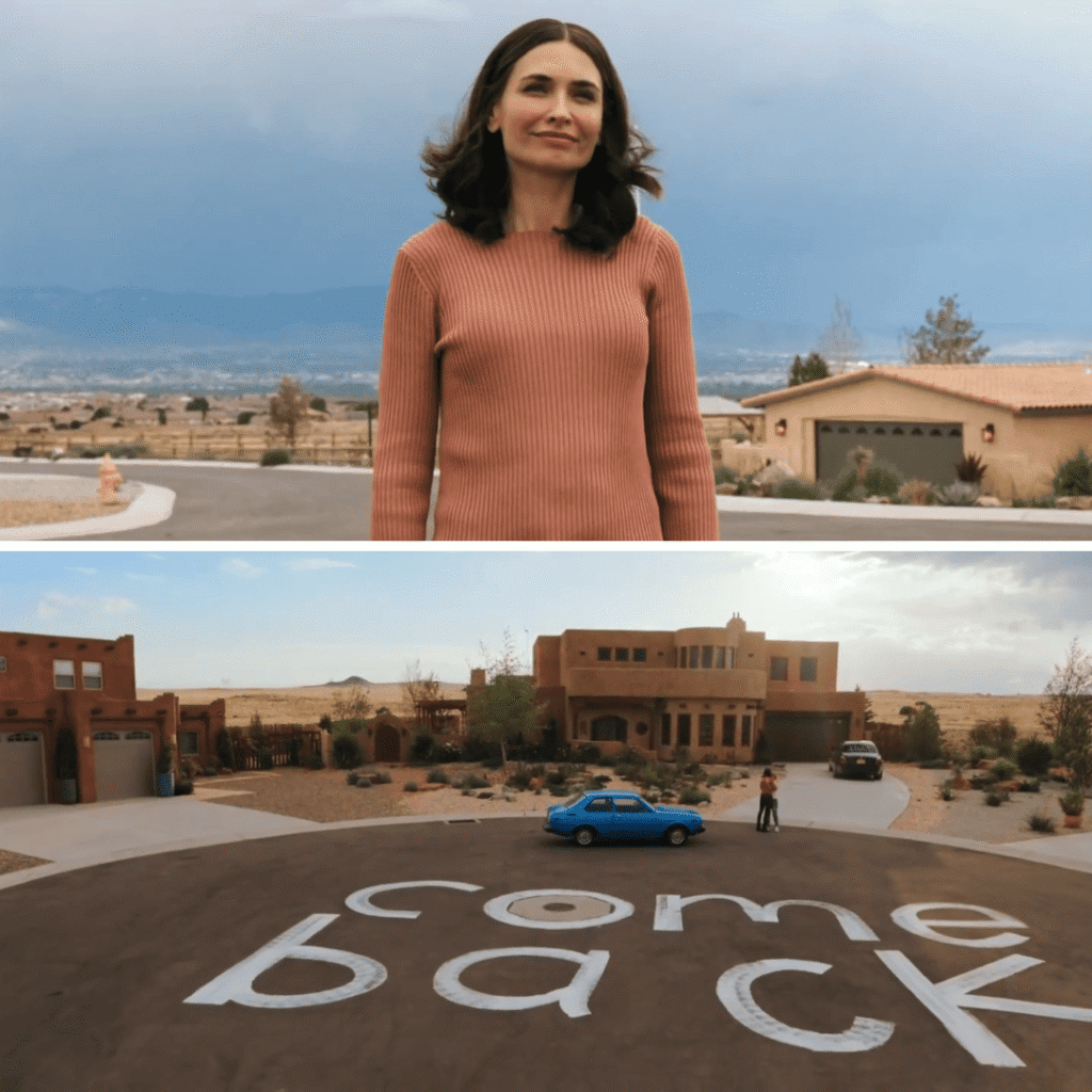 Pluribus Explained: Zosia stands outside Carol’s place after the isolation period, near the white painted message that reads Come Back.