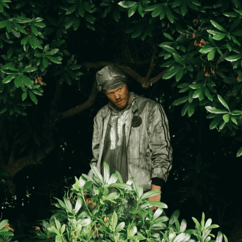 Bugonia Review: Teddy standing alone among the trees, surrounded by quiet stillness after the chaos he helped unleash.