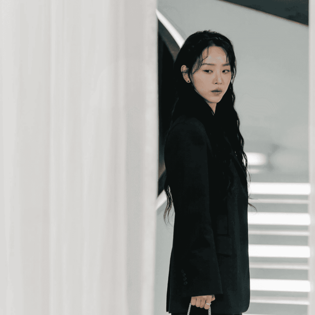 Still of Sarah Kim standing in the doorway of her store’s fitting rooms, a haunting image for The Art of Sarah Character Analysis.