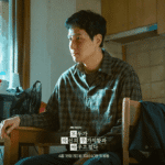 JTBC still of a quiet character portrait for the We Are All Trying Here review showing Park Hae-joon as Hwang Jin-man sitting heavily in a wooden chair while wearing a simple checkered shirt.