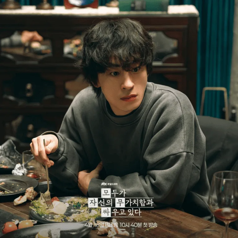A production still for the We Are All Trying Here review released by JTBC, featuring Koo Kyo-hwan as Hwang Dong-man sitting at a restaurant table with a plate of food in front of him.