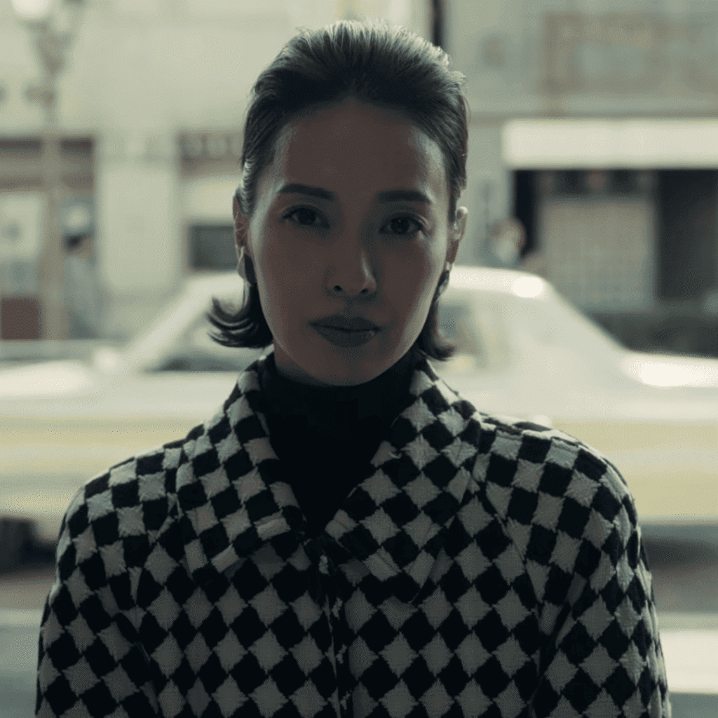 A pivotal scene image for the Straight to Hell review showing Kazuko Hosoki in a checkered jacket sitting in an alleyway, deep in discussion with a fortune-teller about her future Six Star Astrology.