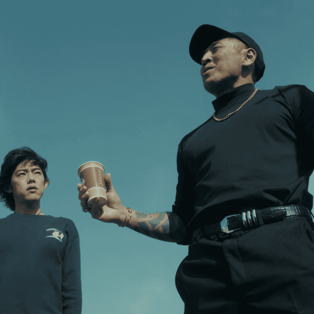 A high-tension still for the Sins of Kujo review featuring Sugawara threatening Kuga while casually holding a cup of coffee.