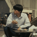 A grounded still for the Sins of Kujo review showing Karasuma eating on the roof, reflecting on the moral weight of his work.