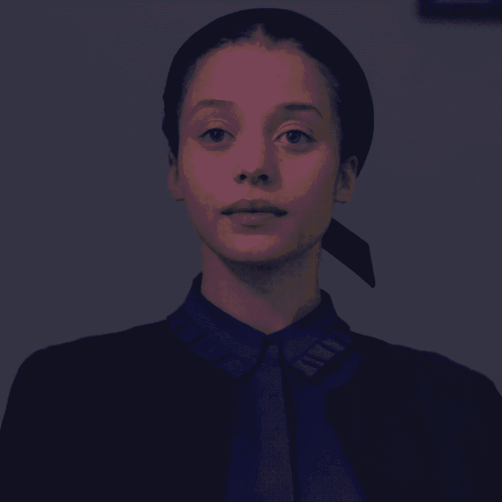 A close-up still image of Agnes dressed as a Plum Girl standing on the staircase inside her home for The Testaments Review.