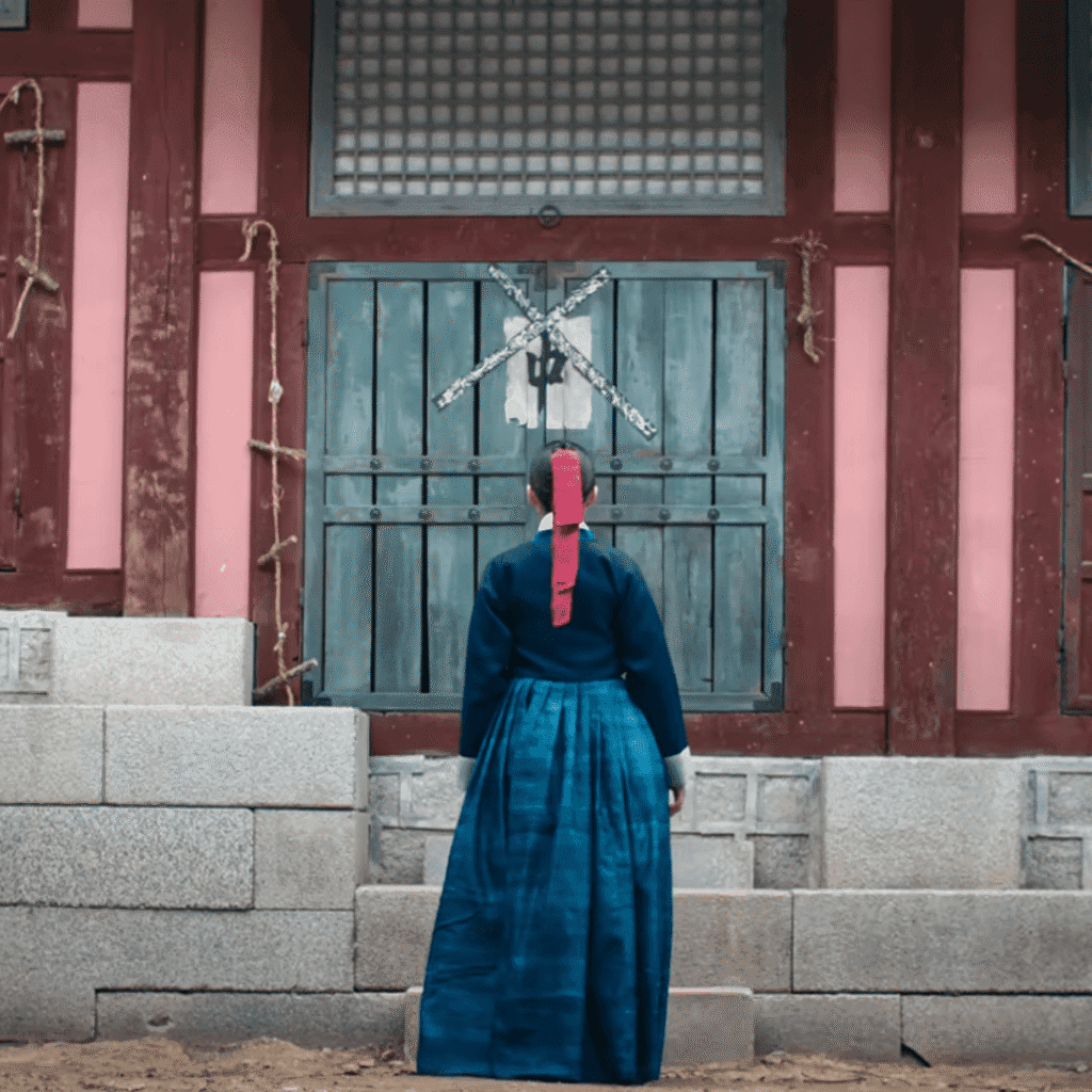 A close-up rear still shot from The East Palace mid-season review showing Saeng-gang standing alone outside the entrance of the desolate salt storage room where the court ladies were massacred.